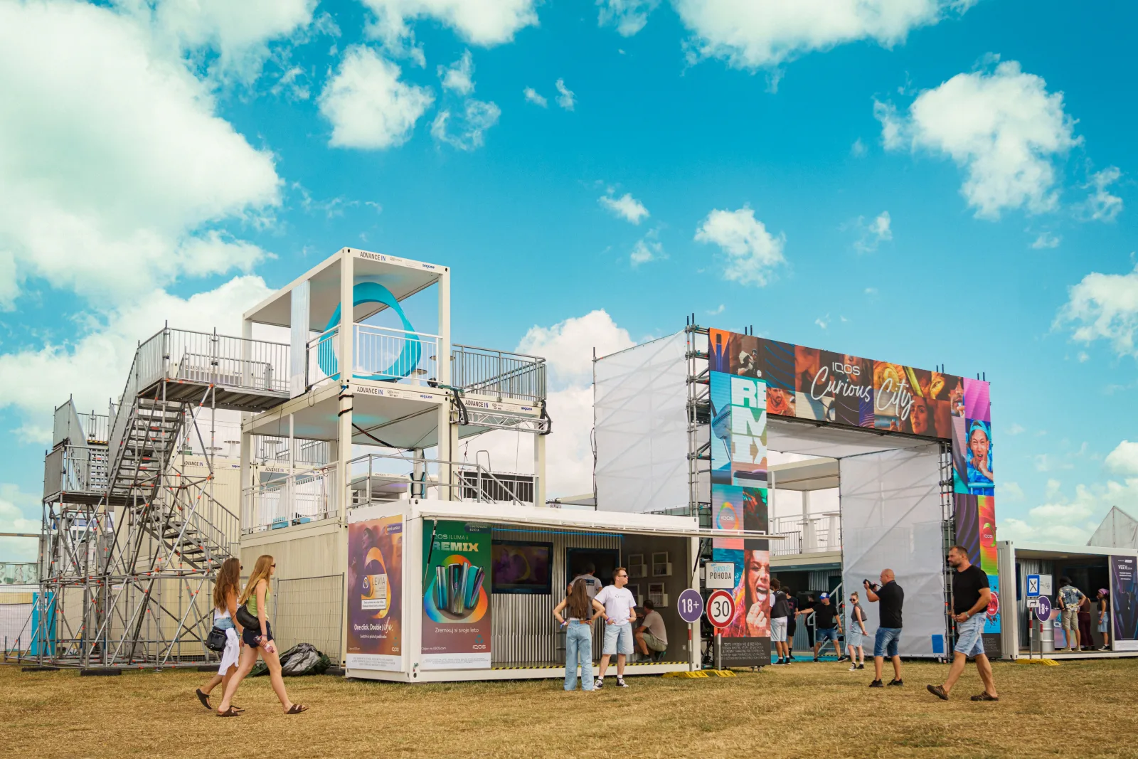 Kontajnerová zóna IQOS Curious City na festivale Pohoda 2025 za slnečného dňa – viacposchodová stavba s brandingom IQOS Remix a Curious City