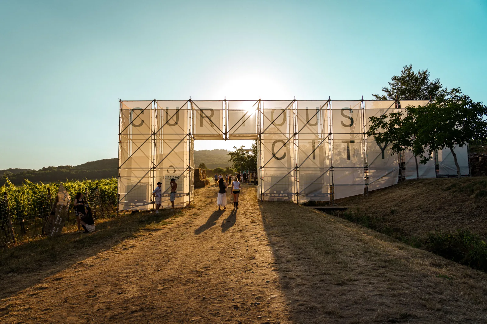 Vstupná brána zóny IQOS Curious City na festivale Ženy Víno Funk pri západe slnka, uprostred viníc Malých Karpát