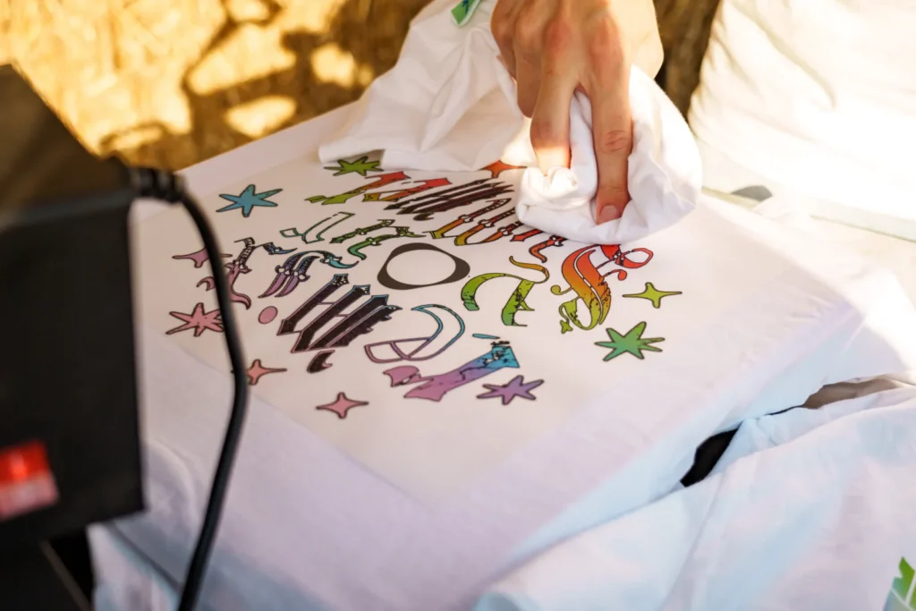 Detail potlače farebnej grafiky na biele tričko pri tvorbe remix merchu v zóne IQOS Curious City