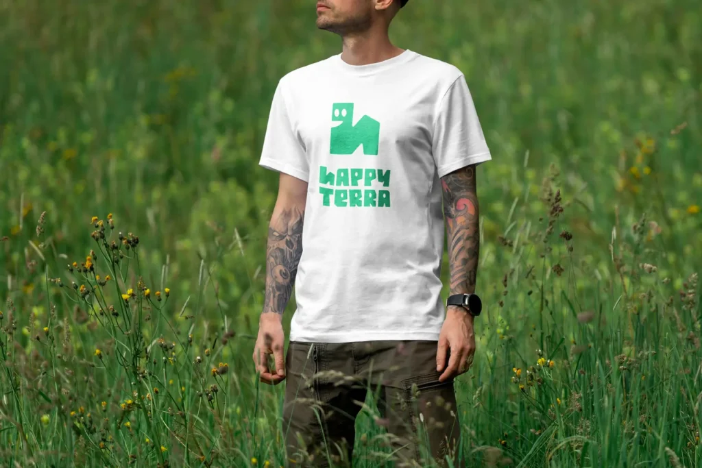 Muž v záhrade oblečený v bielom tričku so zeleno-tyrkysovým logom Happy Terra