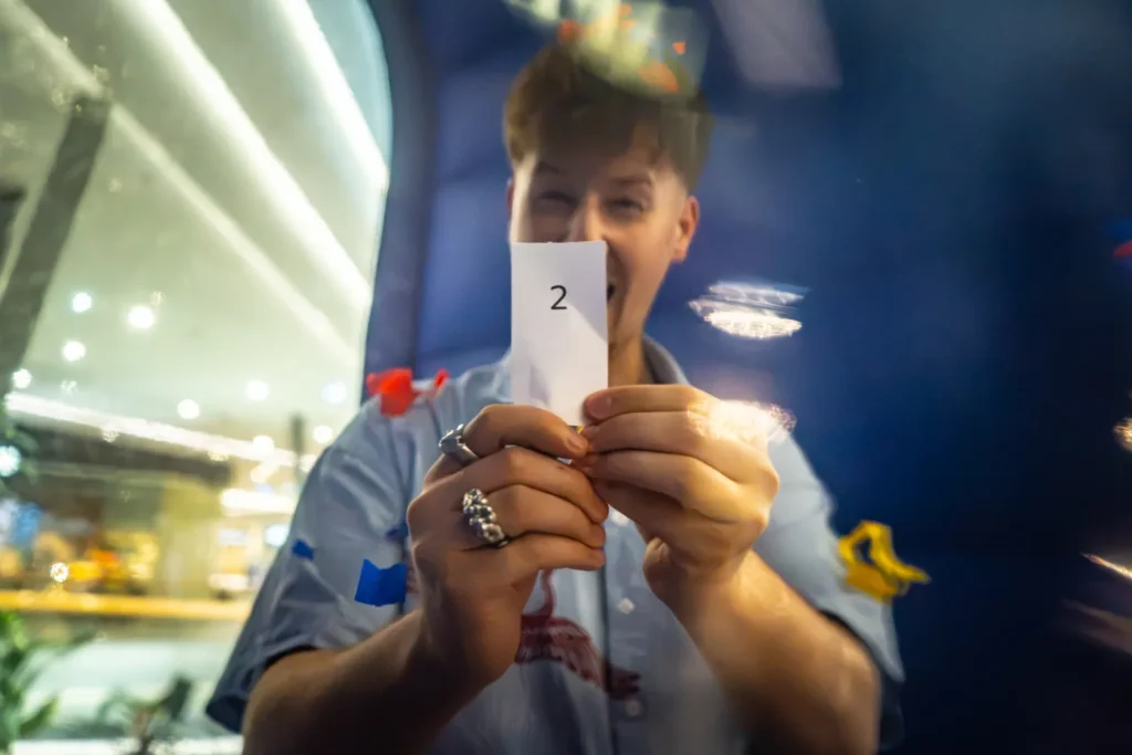 Súťažiaci ukazuje výherný lístok chytený v prúde vetra vo Wind Boxe